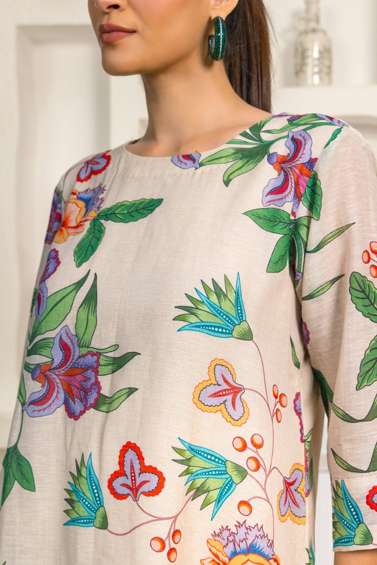 A woman wearing a flowered top and a pair of earrings