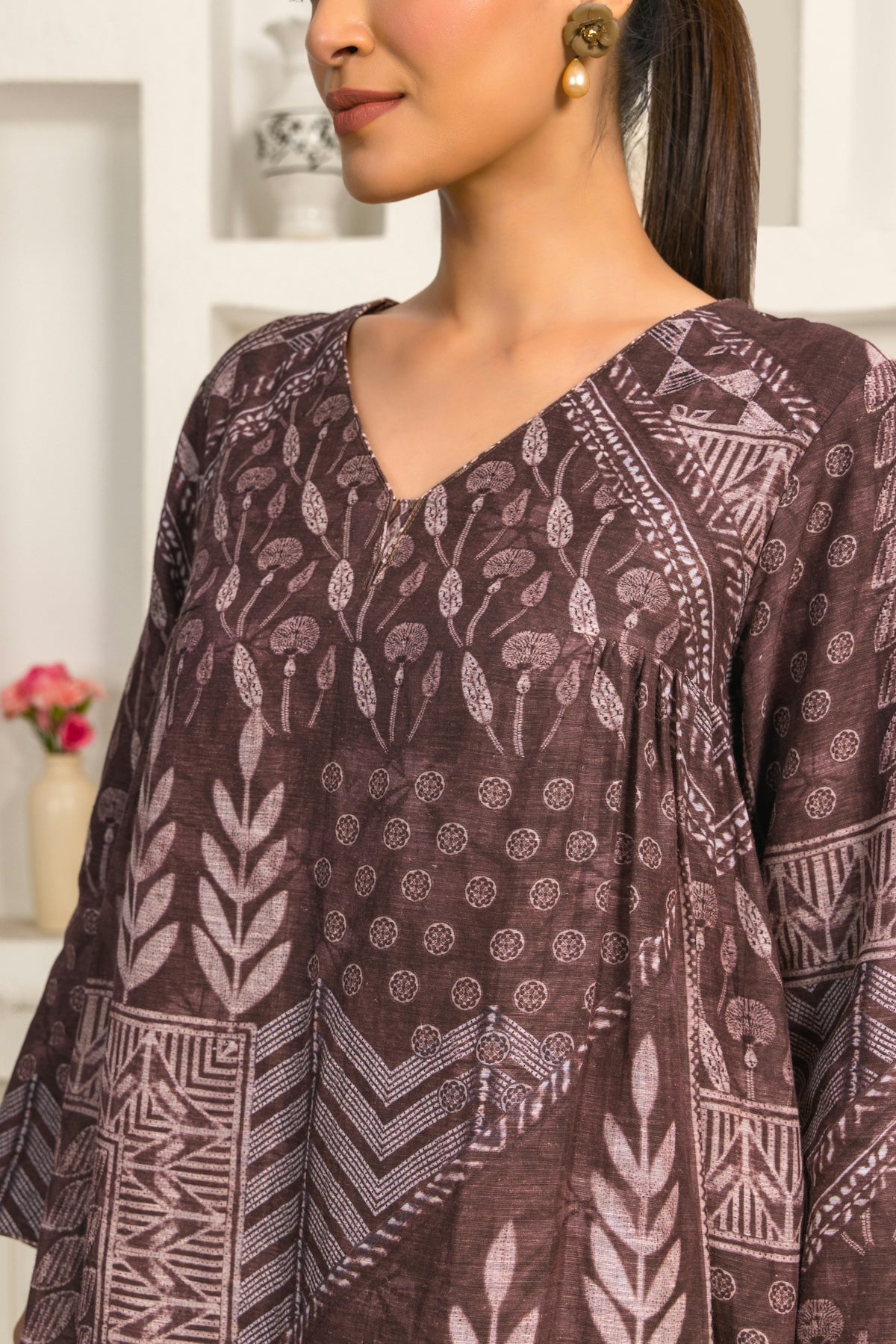 A woman standing in a kitchen wearing a brown top